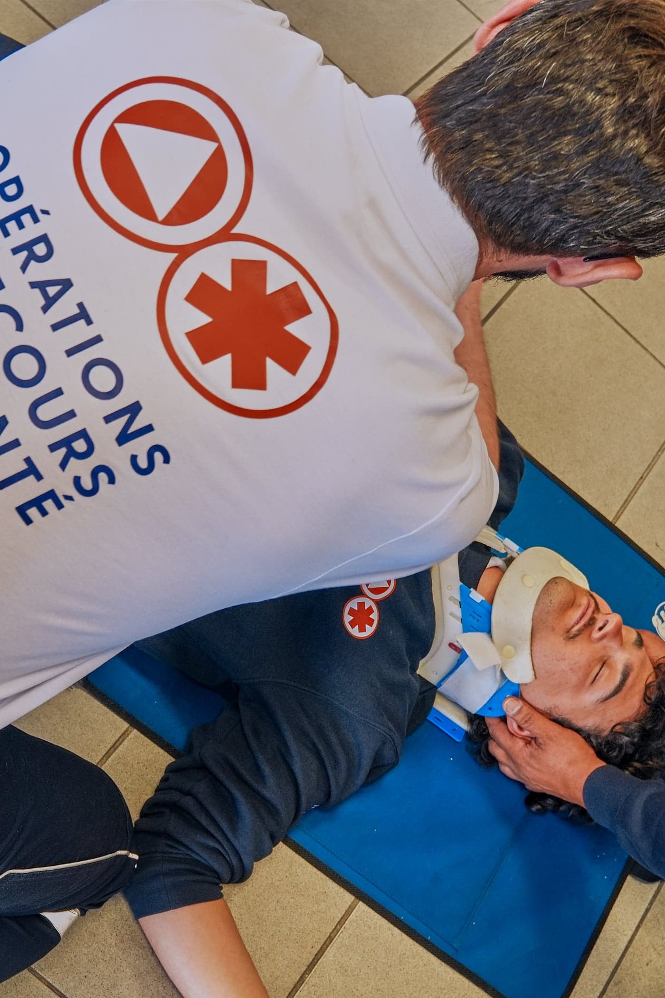 Bénévole OPSAN posant une minerve cervicale sur une victime allongée lors d'un exercice de formation PSE