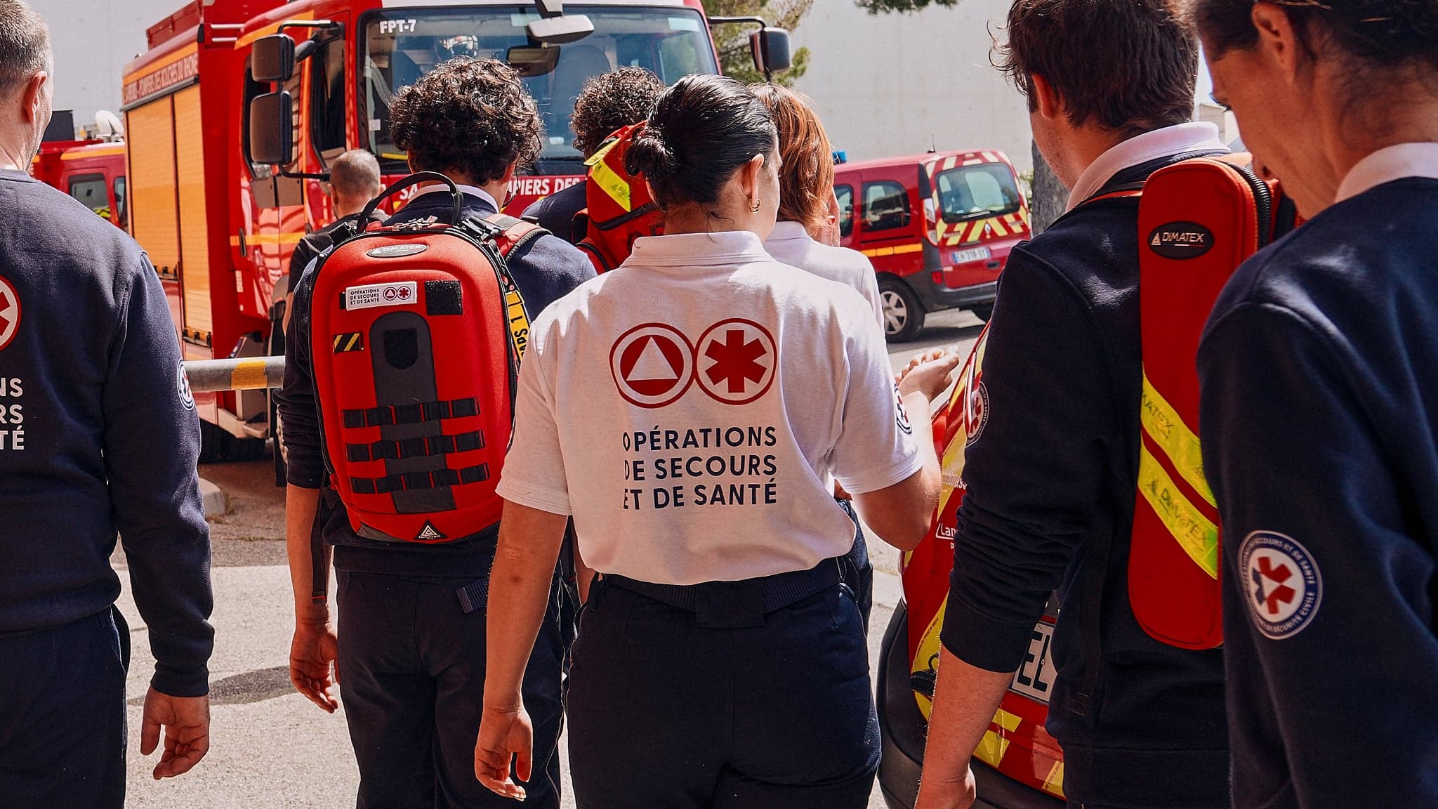 Équipe OPSAN de dos, t-shirt « Opérations de secours et de santé », sacs d'intervention Dimatex et fourgons des Sapeurs-Pompiers du 13
